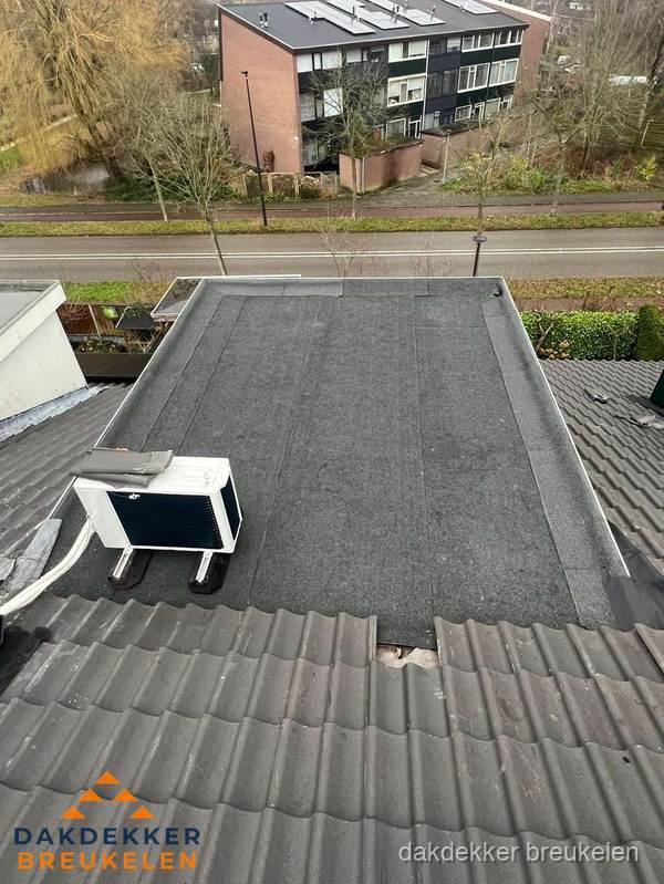 Plat dak inspectie met bitumen bedekking naast schuin pannendak in Breukelen