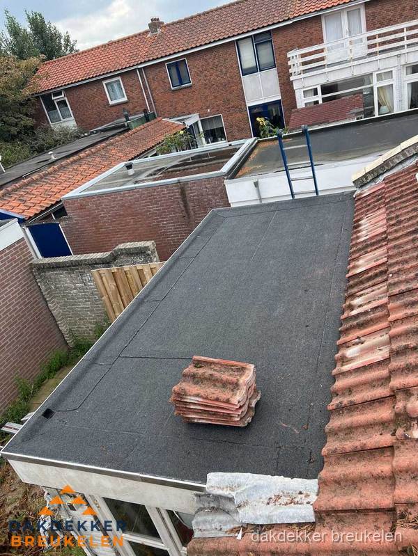 Plat dak aanbouw met bitumen naast schuin pannendak in Breukelen