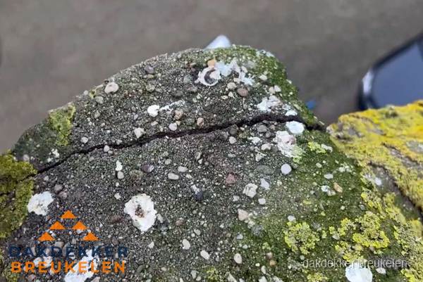 Beschadigde en verweerde nokvorst met scheuren en mos in Breukelen
