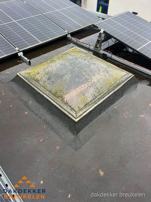 Vervuilde lichtkoepel op plat dak met zonnepanelen in Breukelen
