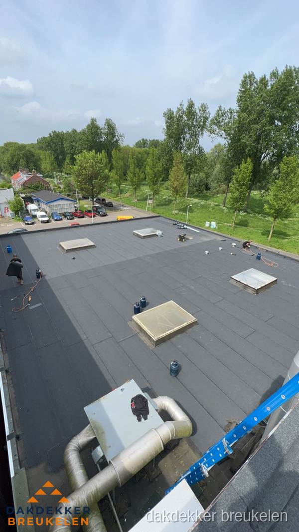 Dakdekker aan het werk op groot plat dak met bitumen in Breukelen